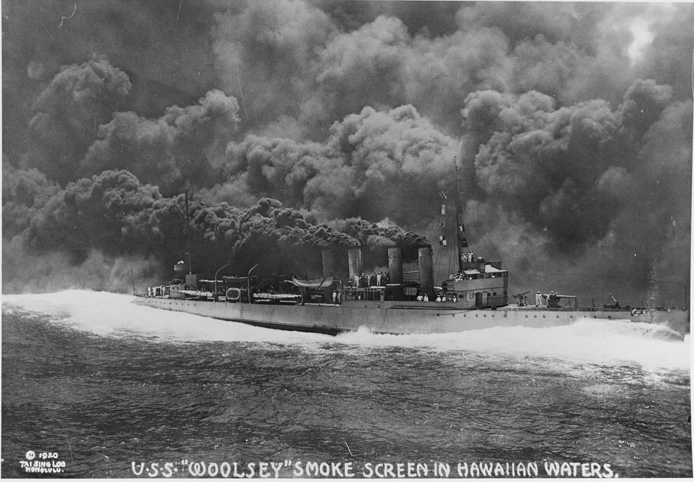 ./PHOTO - USS Woolsey (Destroyer No. 77) Participates in laying a smokescreen, during Pacific Fleet battle practice in Hawaiian waters, circa mid-1919. Photographed by Tai Sing Loo, Honolulu. U.S. Naval History and Heritage Command - NH 7360.png